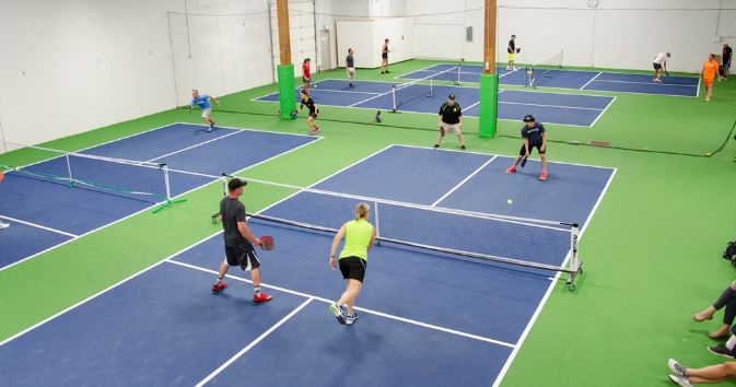 This is an image of indoor pickleball courts with people playing on each court.  